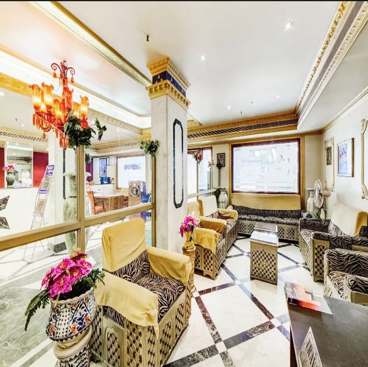 Lobby lounge with patterned armchairs, pink flowers and a red chandelier