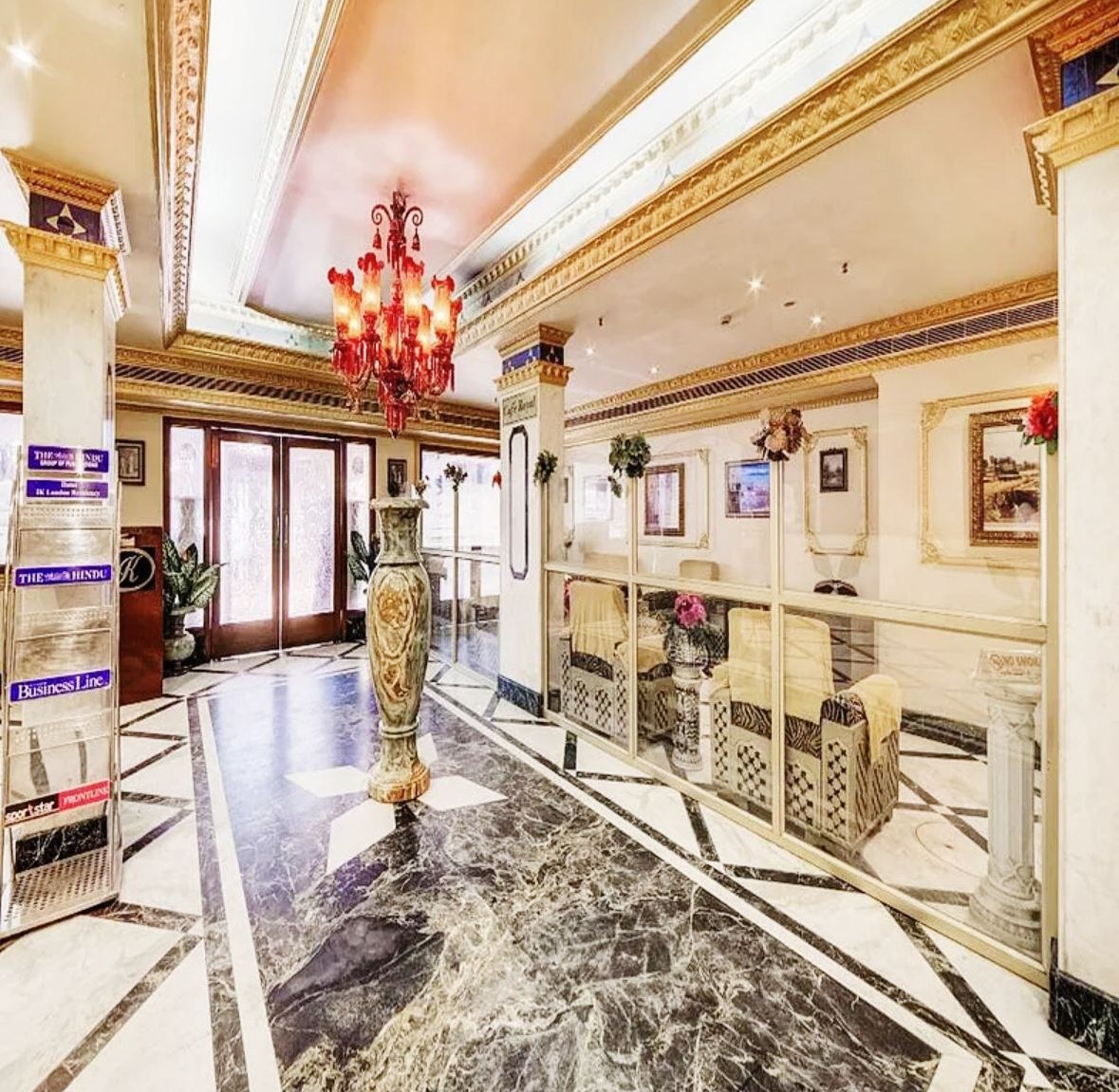 The hotel lobby with a red chandelier, gold cornices and a tall decorative vase